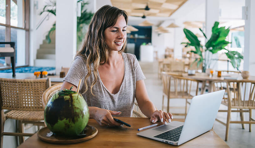 Woman with laptop in café with coconut drink