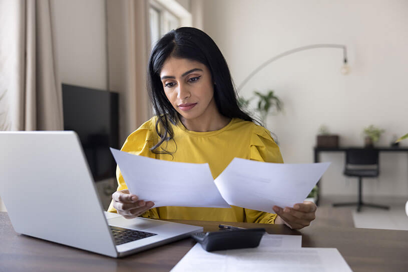 Woman looking at receipts in order to digitally submit her income tax report on a laptop