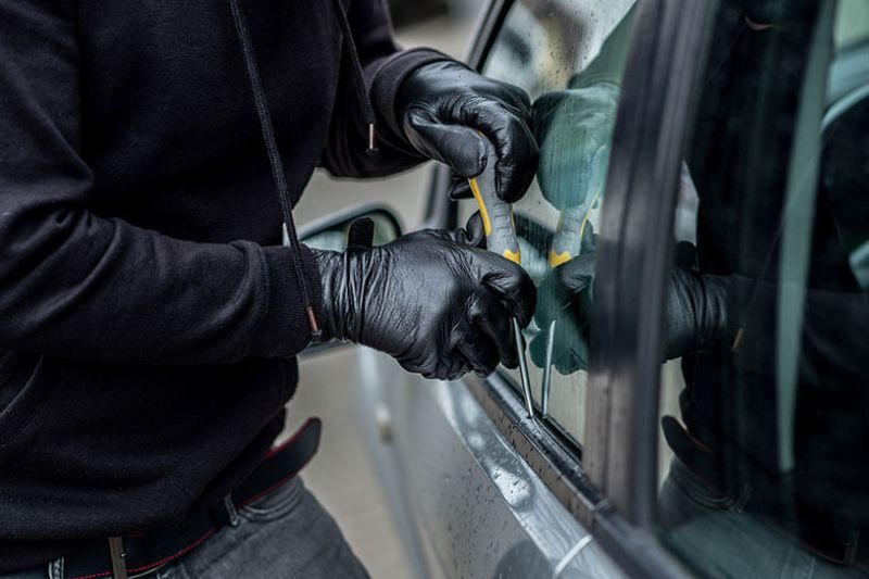 Gloved hands breaking into a vehicle
