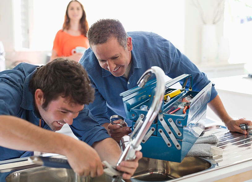 Two plumbers, a vanishing trade, work together on a sink