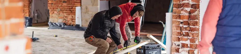 Two men measuring a piece of wood