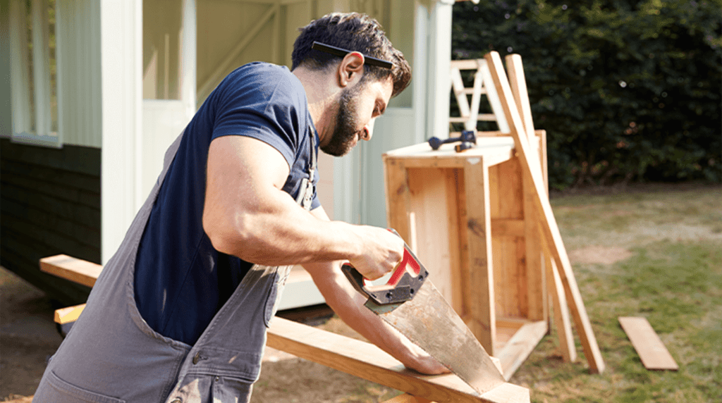 A carpenter sawing wood outside